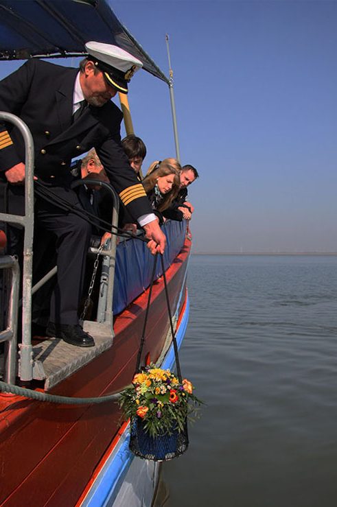 Seebestattung mit Angehörige Ein Kapitän lässt die geschmückte Seeurne ins Wasser.